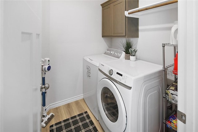 laundry area featuring cabinets, hardwood / wood-style flooring, and separate washer and dryer