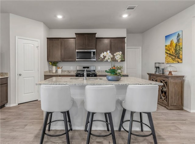 2412 Divot Ln, Navasota, TX 77868 - kitchen with stainless steel appliances, a breakfast bar, a center island with sink, and dark brown cabinetry