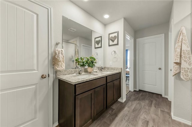 2412 Divot Ln, Navasota, TX 77868 - full bathroom with double vanity, wood finished floors, baseboards, and a shower with shower door