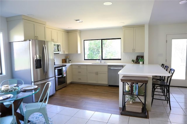 kitchen featuring light wood-type flooring, stainless steel appliances, plenty of natural light, and sink