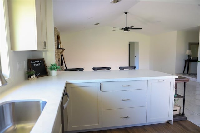 kitchen featuring white cabinets, dark hardwood / wood-style flooring, kitchen peninsula, and lofted ceiling