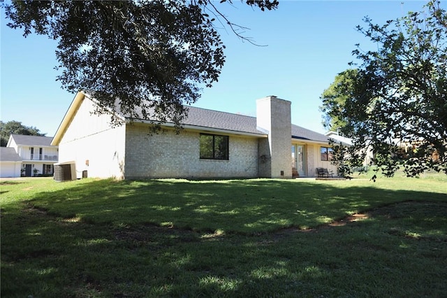 rear view of property with central AC unit and a yard