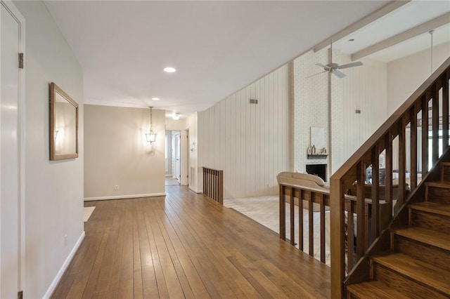 interior space with ceiling fan, wood-type flooring, a fireplace, and wooden walls