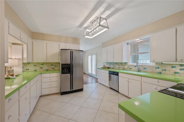 kitchen with backsplash, white cabinets, sink, light tile patterned floors, and appliances with stainless steel finishes