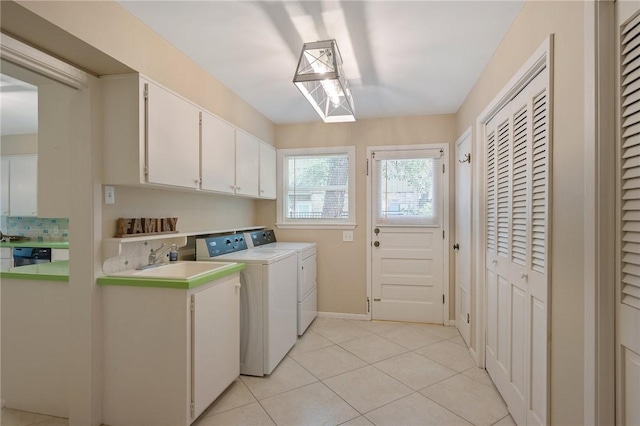 laundry room featuring cabinets, light tile patterned floors, sink, and washing machine and clothes dryer