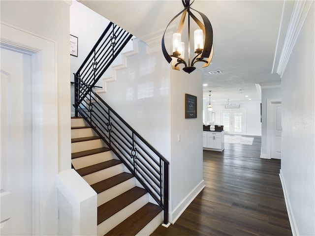 stairs with hardwood / wood-style flooring, french doors, crown molding, and an inviting chandelier