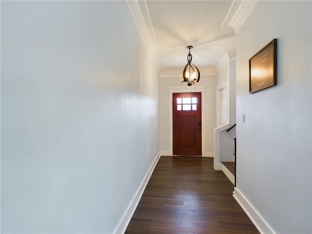 entryway with an inviting chandelier, dark hardwood / wood-style floors, and ornamental molding