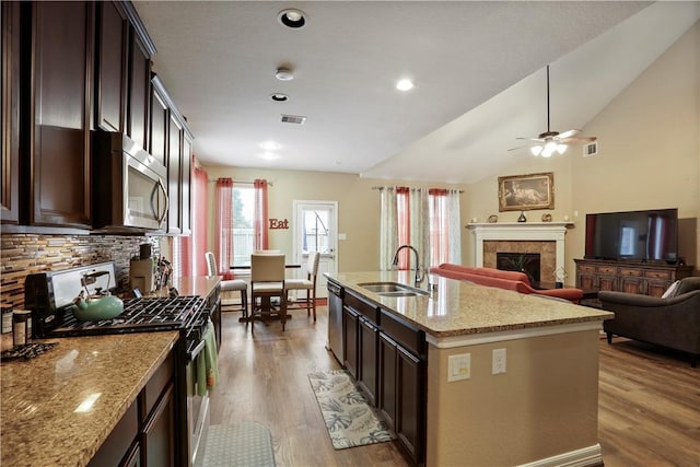 kitchen with appliances with stainless steel finishes, hardwood / wood-style flooring, light stone counters, and sink