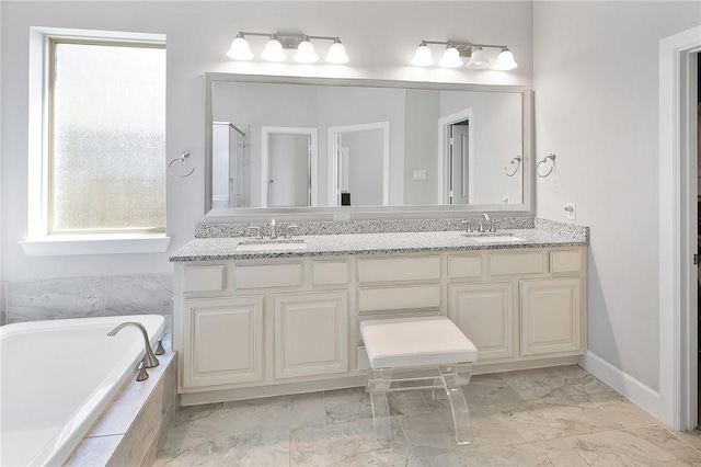 bathroom with double vanity, marble finish floor, tiled bath, and a sink