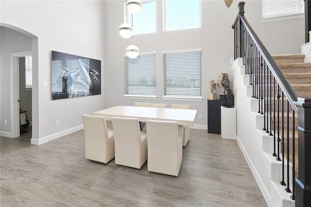 dining room with arched walkways, light wood finished floors, and plenty of natural light