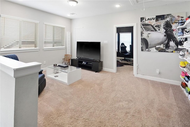 living area featuring attic access, baseboards, and light colored carpet