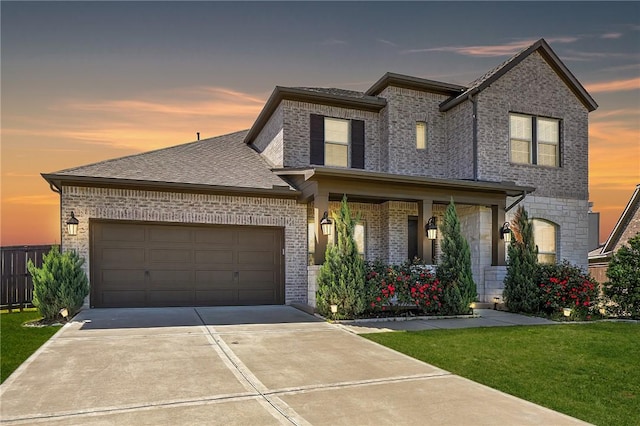 view of front facade with brick siding, a shingled roof, concrete driveway, a lawn, and an attached garage