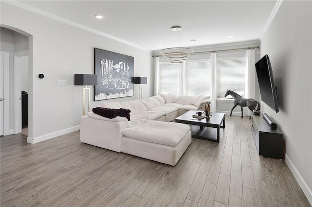 living area featuring baseboards, arched walkways, wood finished floors, and ornamental molding