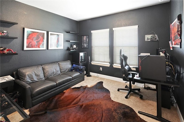 carpeted home office featuring a textured wall and baseboards