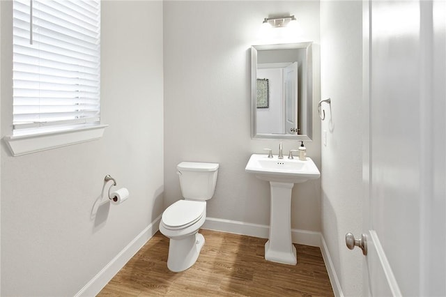 half bath featuring toilet, baseboards, and wood finished floors