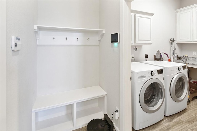 washroom with cabinet space, light wood-style floors, and washer and dryer