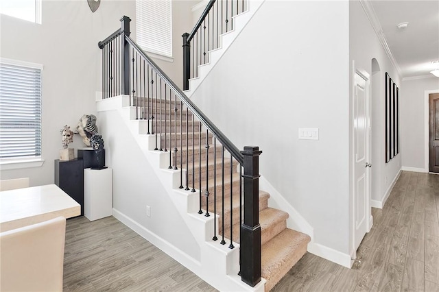 stairs with crown molding, baseboards, and wood finished floors