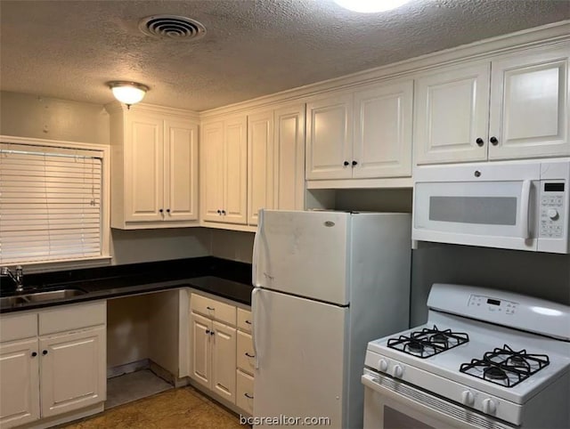 kitchen with white appliances, white cabinets, tile patterned floors, sink, and a textured ceiling