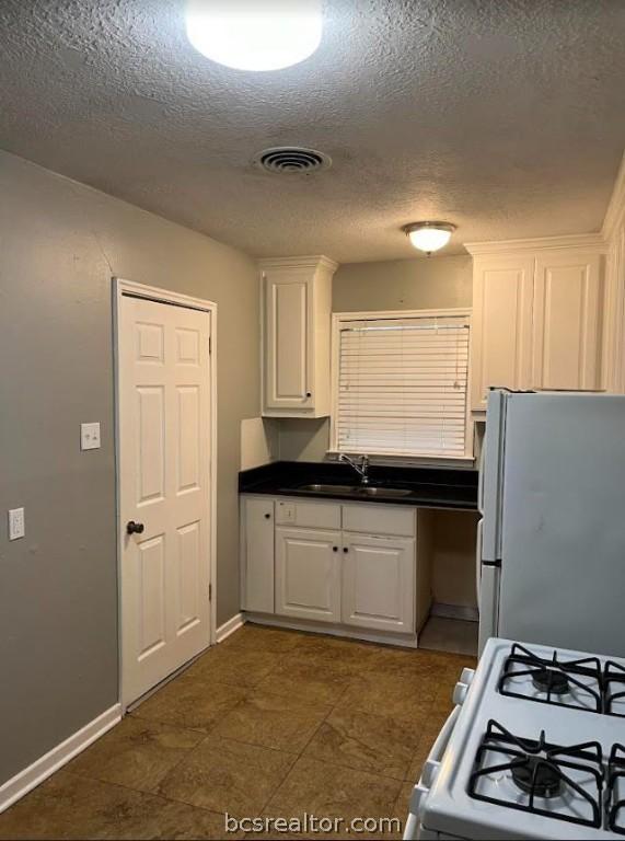 kitchen featuring white cabinets, white appliances, sink, and a textured ceiling