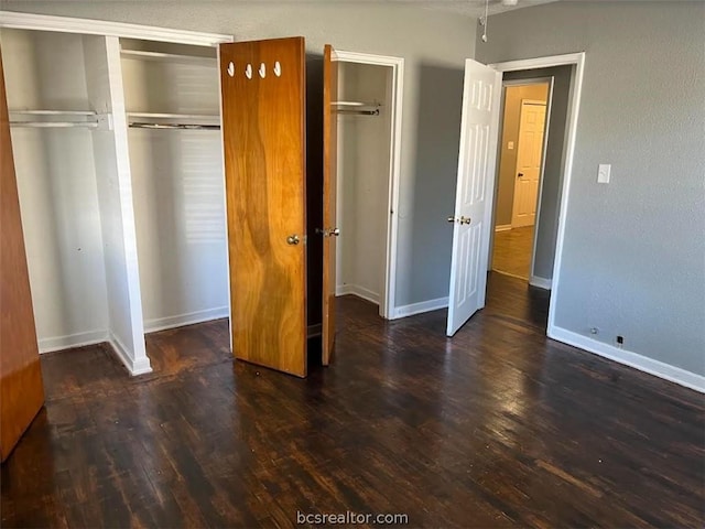 unfurnished bedroom with dark hardwood / wood-style flooring and two closets