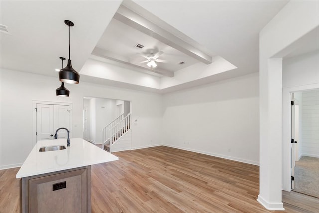 kitchen featuring ceiling fan, sink, hanging light fixtures, an island with sink, and light hardwood / wood-style floors