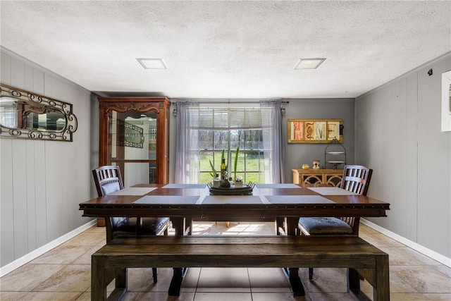 dining area featuring baseboards, a textured ceiling, and light tile patterned flooring