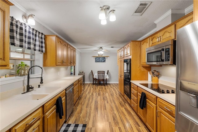 kitchen featuring black appliances, ornamental molding, visible vents, and a sink