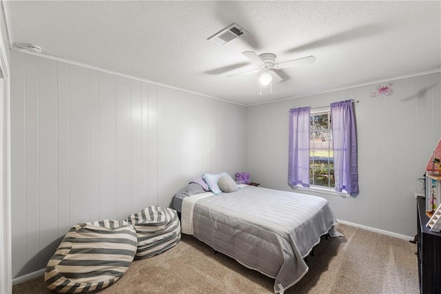 carpeted bedroom featuring visible vents, baseboards, ornamental molding, a textured ceiling, and a ceiling fan