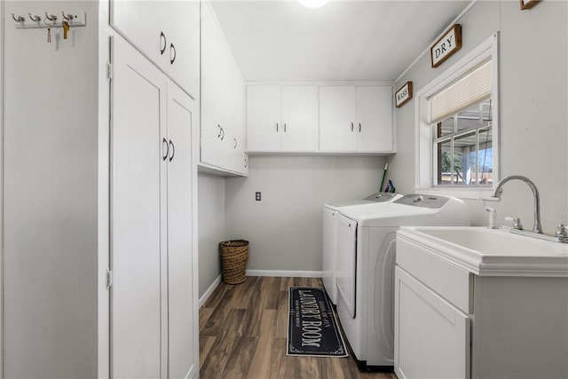 washroom with dark wood-type flooring, a sink, cabinet space, separate washer and dryer, and baseboards