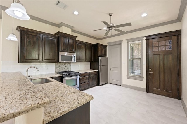 5217 Ruddy Duck Dr, College Station, TX 77845 - kitchen with stainless steel appliances, a ceiling fan, decorative backsplash, light stone countertops, and dark brown cabinetry