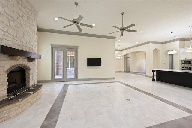 5217 Ruddy Duck Dr, College Station, TX 77845 - unfurnished living room featuring crown molding, a ceiling fan, a fireplace, arched walkways, and light tile patterned floors