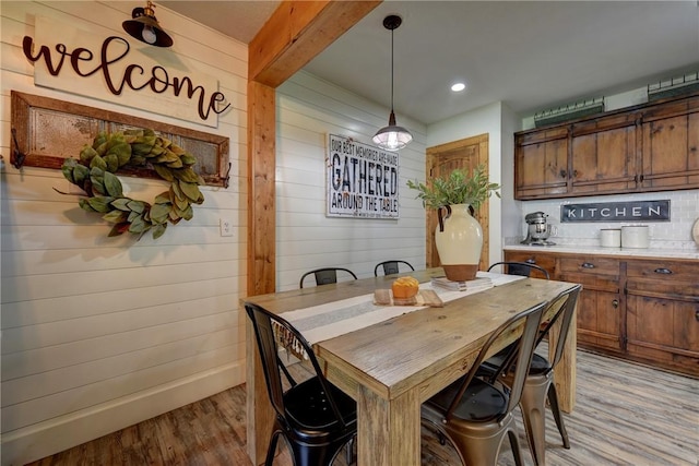 dining room featuring light hardwood / wood-style floors and wooden walls