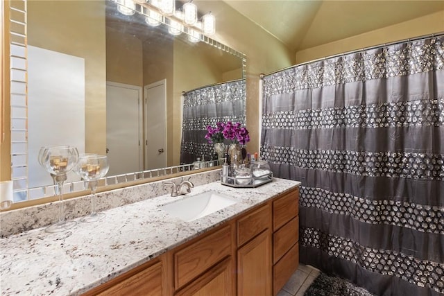 bathroom with lofted ceiling, vanity, and tile patterned flooring