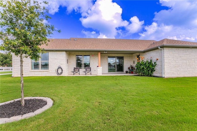 rear view of property featuring a lawn and a patio