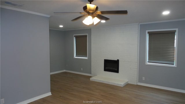 unfurnished living room featuring ceiling fan, wood-type flooring, a fireplace, and ornamental molding