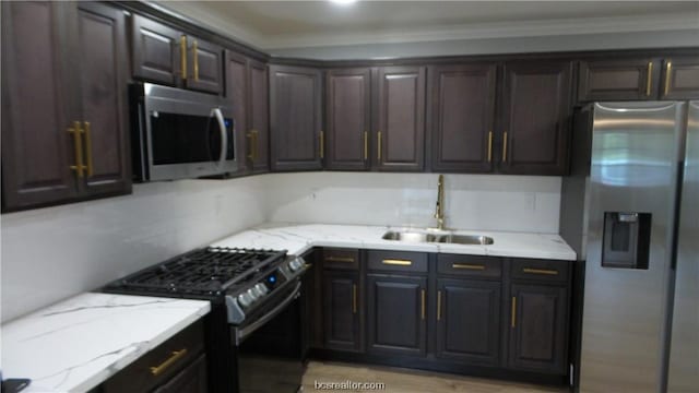 kitchen with dark brown cabinetry, stainless steel appliances, light stone counters, and sink