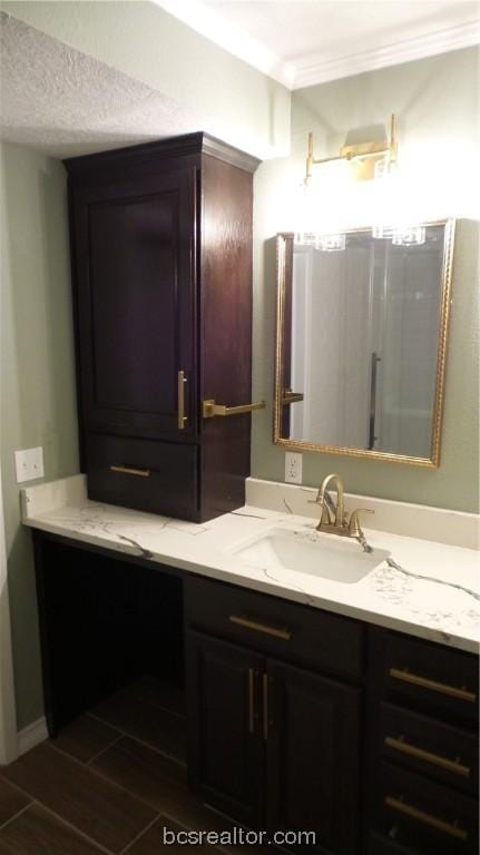 bathroom featuring hardwood / wood-style flooring, vanity, ornamental molding, and a textured ceiling