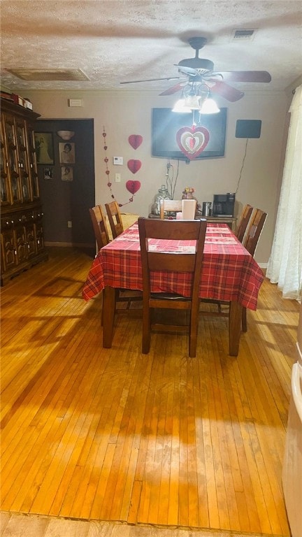 dining area with hardwood / wood-style flooring, ceiling fan, and a textured ceiling