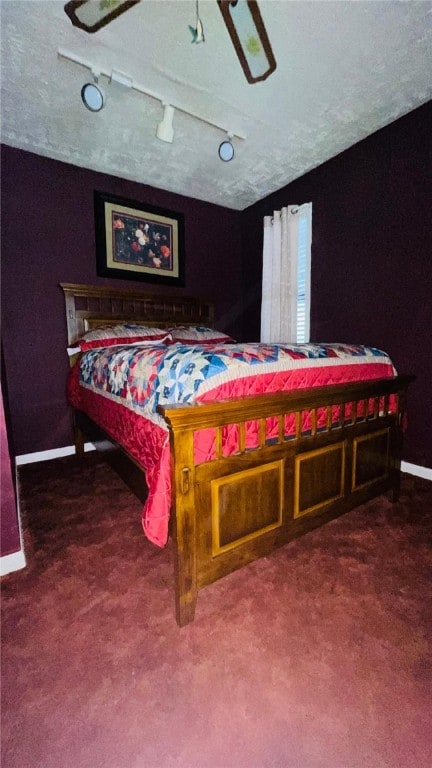 bedroom with lofted ceiling, rail lighting, a textured ceiling, dark carpet, and ceiling fan