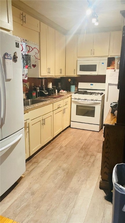 kitchen featuring sink, white appliances, cream cabinets, and light wood-type flooring