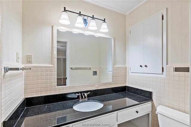 bathroom with vanity, toilet, ornamental molding, and tile walls