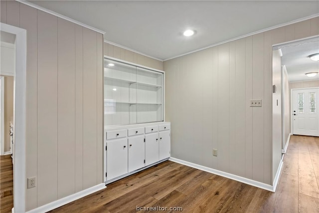 interior space featuring hardwood / wood-style floors, ornamental molding, and wood walls