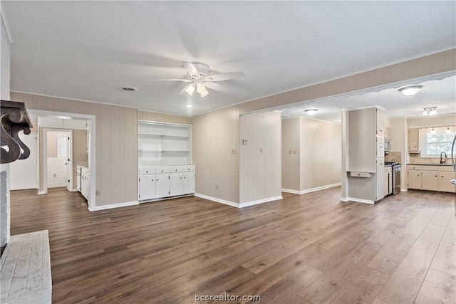 unfurnished living room with ceiling fan, dark hardwood / wood-style flooring, ornamental molding, and sink