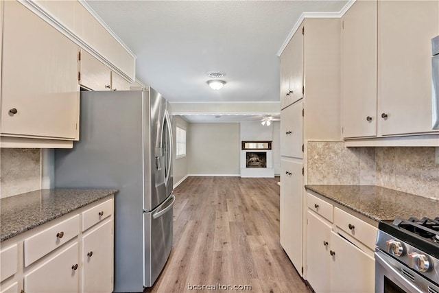 kitchen with light hardwood / wood-style flooring, dark stone countertops, ornamental molding, tasteful backsplash, and stainless steel appliances