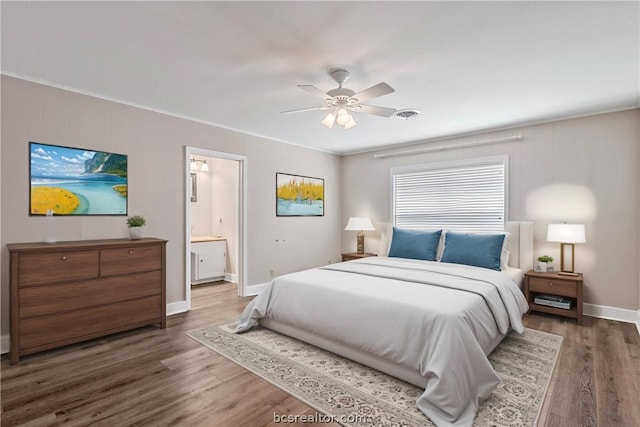 bedroom featuring dark hardwood / wood-style floors, ceiling fan, crown molding, and ensuite bath