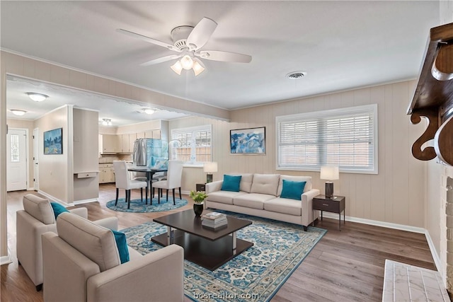 living room featuring crown molding, ceiling fan, and light hardwood / wood-style floors