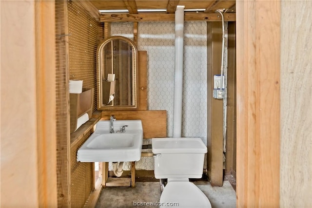 bathroom featuring toilet, concrete flooring, and sink