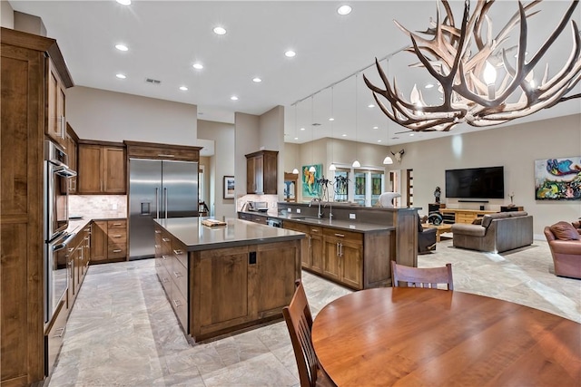 kitchen featuring decorative backsplash, kitchen peninsula, stainless steel appliances, sink, and a center island