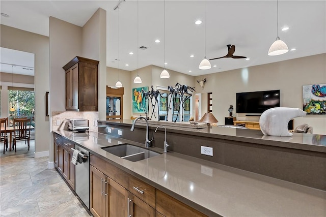 kitchen featuring backsplash, stainless steel dishwasher, ceiling fan, sink, and decorative light fixtures