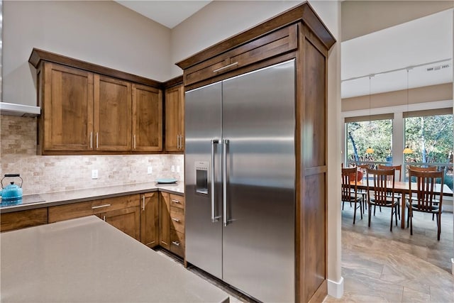 kitchen with tasteful backsplash, built in refrigerator, and pendant lighting